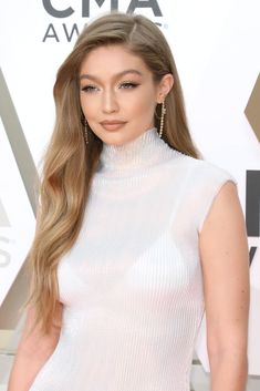 a woman with long hair wearing a white top and black pants at the cma awards