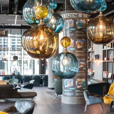 several glass balls hanging from the ceiling in a room with yellow chairs and couches