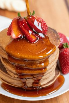 a stack of pancakes covered in syrup and strawberries