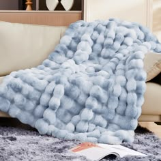 a large fluffy blue blanket sitting on top of a couch next to a white pillow