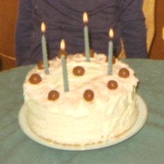 a young boy sitting in front of a cake with lit candles on it and looking at the camera