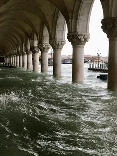 an underpass with columns and water in the foreground