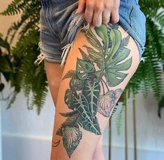 a woman's legs with tattoos on them and flowers in the bottom part of her thigh