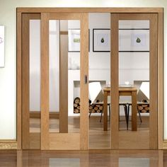 an open glass door in a room with wooden floors and white walls, showing the dining area