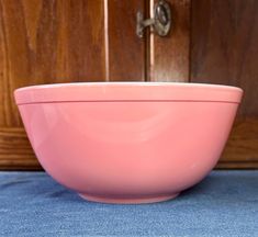 a pink bowl sitting on top of a blue table cloth next to a wooden door