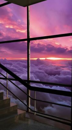 the sun is setting over some clouds from an observation point in the sky, with stairs leading up to it