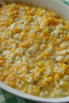 a casserole dish with corn and cheese in it on a checkered table cloth