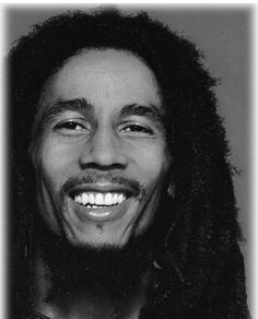 a black and white photo of a man with dreadlocks smiling at the camera