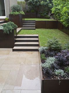 an outdoor garden with steps leading up to the grass and flowers on the side walk