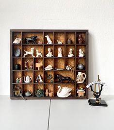 a wooden shelf filled with lots of figurines on top of a white table