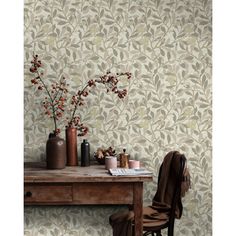 a desk with a chair and vases on it next to a wallpapered wall