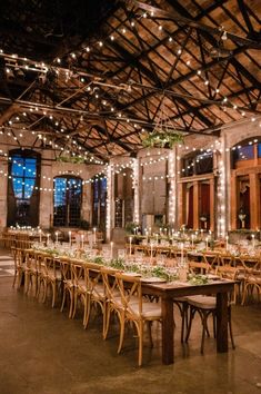 a long table with candles and greenery is set up in the middle of an old building