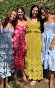 four women standing next to each other in dresses