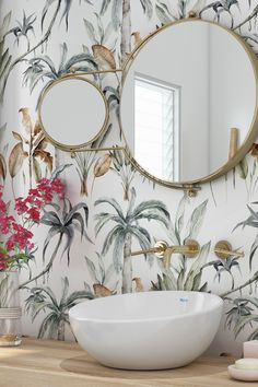 a white sink sitting under a round mirror next to a wall mounted faucet