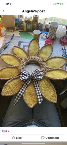 a person sitting at a table with a large flower made out of straw and ribbon