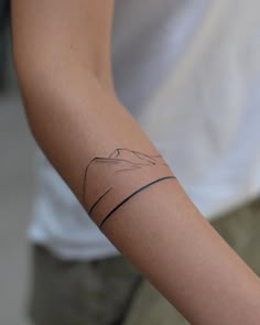 a woman's arm with a tattoo on it that has mountains in the background