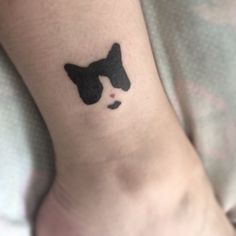 a small black and white cat tattoo on the ankle, which has been drawn onto someone's leg