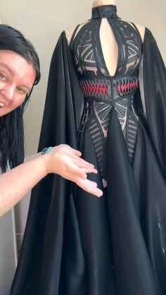 a woman standing next to a black dress on a mannequin's dummy