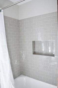 a white bath tub sitting under a window next to a shower curtain in a bathroom