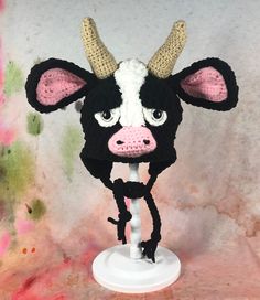 a crocheted cow head with horns on top of a white stand against a wall