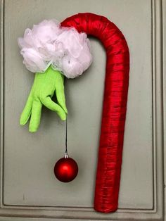 a green hand hanging from the side of a door with a red ornament