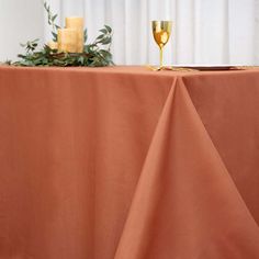 a table topped with a gold candle and a vase filled with flowers on top of it