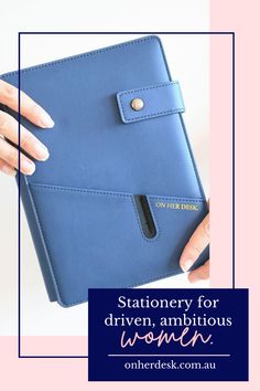 a woman's hand holding a blue notebook with the words stationery for driven, ambitious women on it