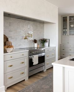 A light and bright kitchen, neutral kitchen cabinets with beautifully staged kitchen decor. Light grey cabinets. Large textured range hood. Counter Tops, Kitchen Tiles, Beautiful Kitchens, Tile Backsplash, Kitchen Backsplash