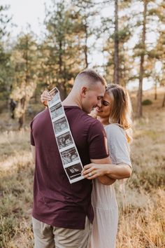 a man and woman hugging each other in the woods with an old photo hanging from their neck