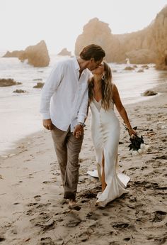 a newly married couple walking on the beach