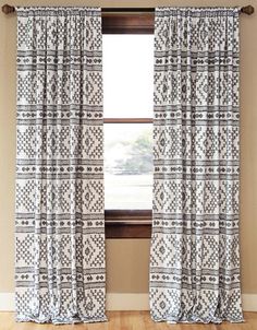 the curtains in this room are made out of white and black patterned fabric, with an open window behind them