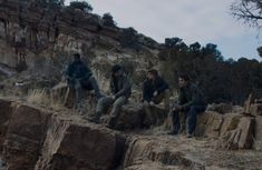 four men sitting on rocks in the desert