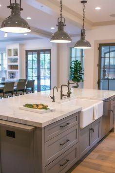 a large kitchen island with two sinks and hanging lights