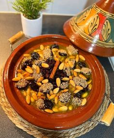 a bowl filled with food sitting on top of a table next to a potted plant