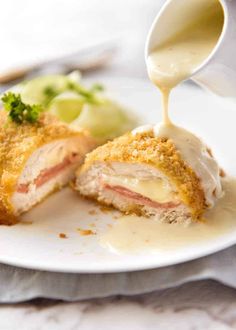 the chicken cordon bleu is being drizzled with sauce