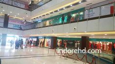 the inside of a shopping mall with people walking around and looking at clothing on display