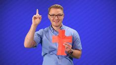 a man holding up an orange paper cross on his left hand and pointing to the right