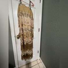 a dress hanging on a door handle in front of a white door with tile flooring