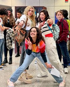 a group of young people standing next to each other in an airport lobby, posing for the camera