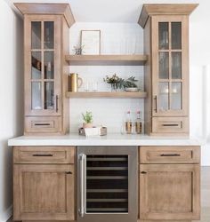 a kitchen with wooden cabinets and white counter tops, an open wine cooler in the center