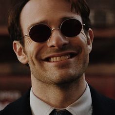 a man wearing sunglasses and a suit smiling