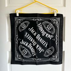 a black bandana hanging on a white door with yellow hooks and the words jack daniels written below it