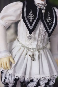 the doll is wearing a white dress with black and silver details on it's chest