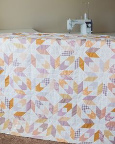 a quilted table top with a sewing machine in the background