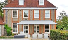 a large brick house with white chairs and an awning