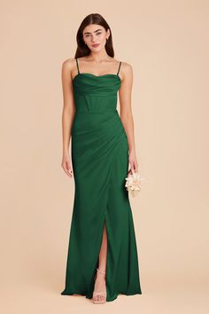 a woman wearing a green bridesmaid dress and holding a bouquet in her hand