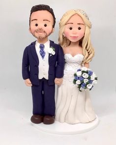 a wedding cake topper with a bride and groom standing next to each other on a white background