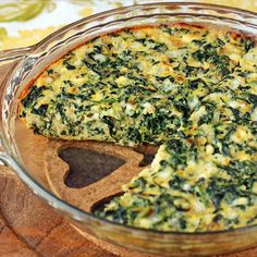 spinach and cheese quiche in a glass dish with a wooden spoon on the side