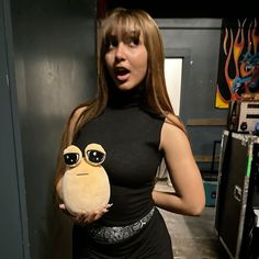 a woman is holding a stuffed animal in front of her face and looking surprised at the camera