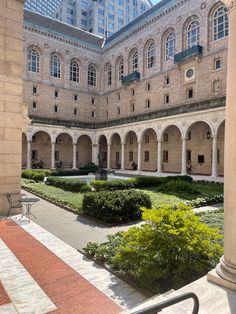 the courtyard of an old building with stone arches and plants growing in the center, surrounded by tall buildings